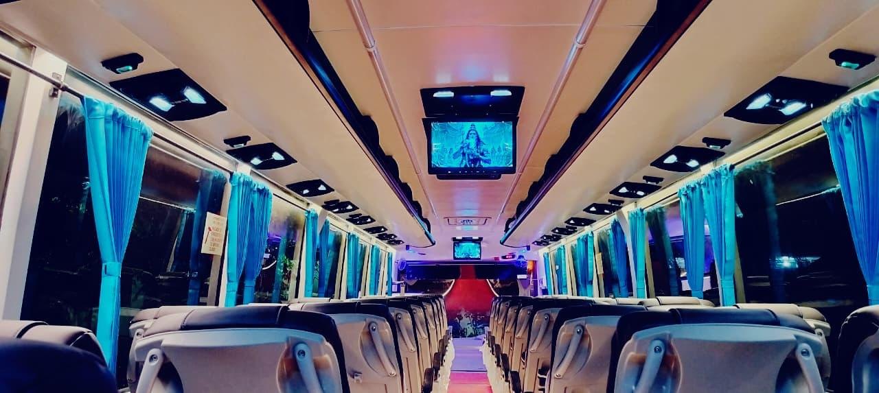 Coach interior at night with overhead screens and soft blue cabin lighting