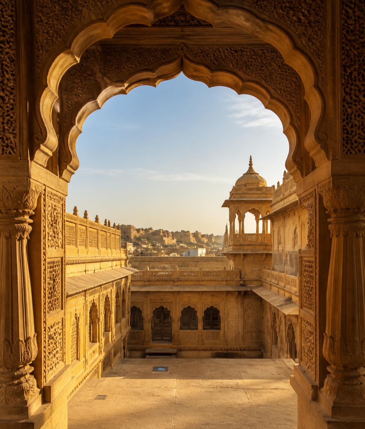 Carved sandstone arches of a Rajasthani palace courtyard in golden light