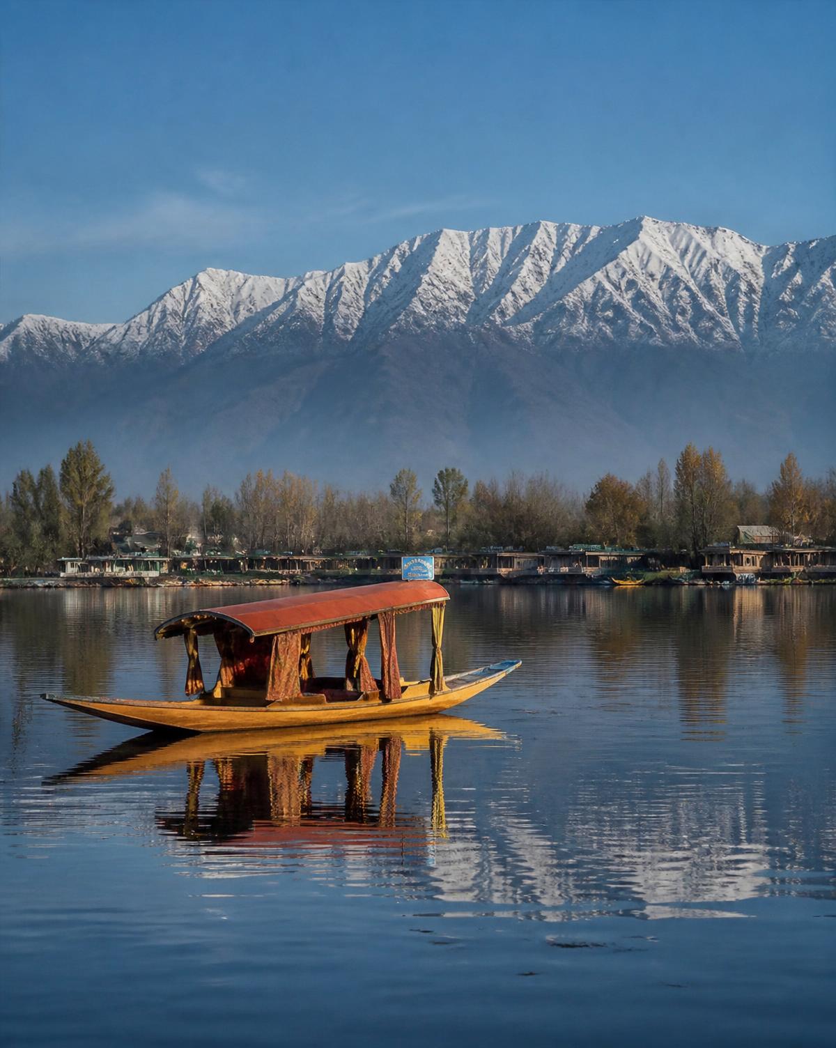 A traditional shikara boat on Dal Lake with snow-capped mountains, Kashmir