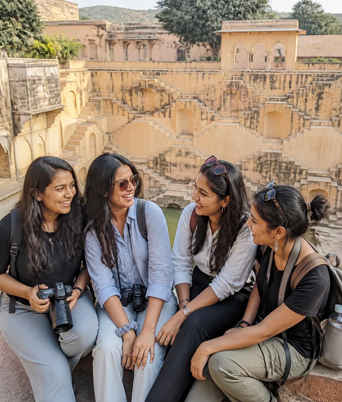Four women friends laughing together while sightseeing at a stepwell in Jaipur